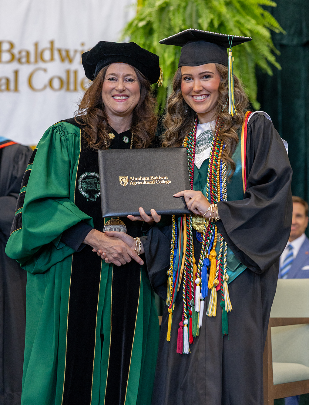 jenna Williams in her cap and gown holding her diploma with Dr. Tracy Brundage