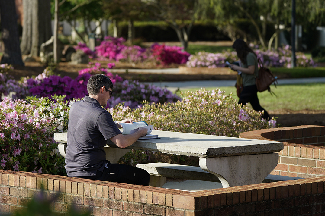 male student sitting at a picnic table studying
