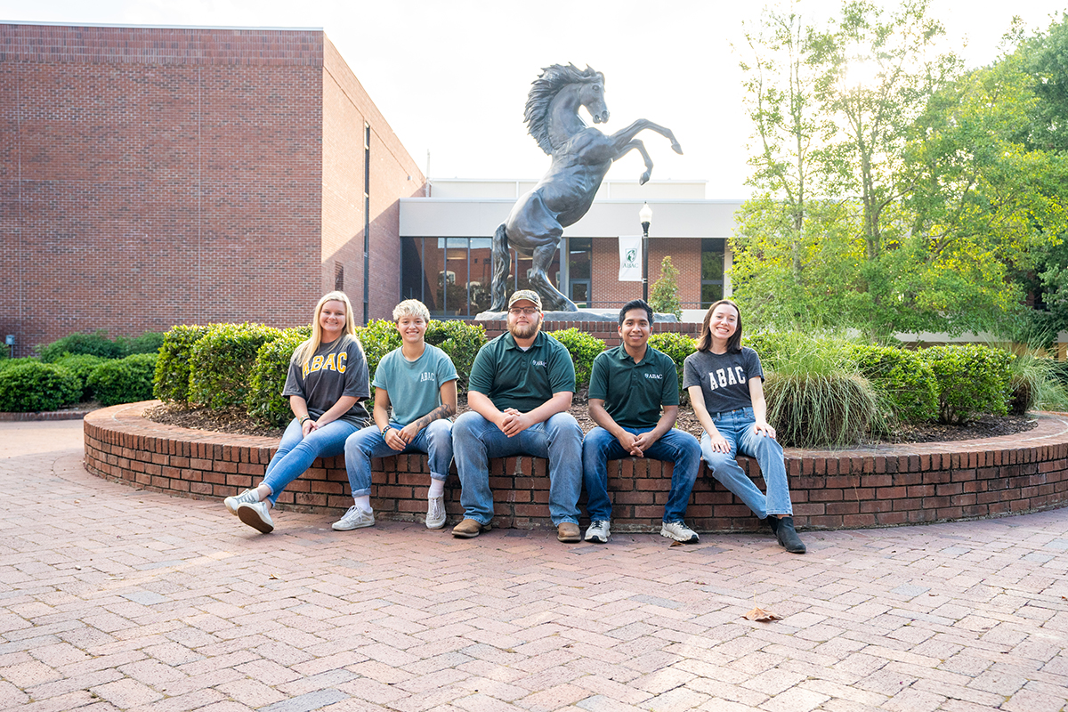 students sitting around the stallion statue