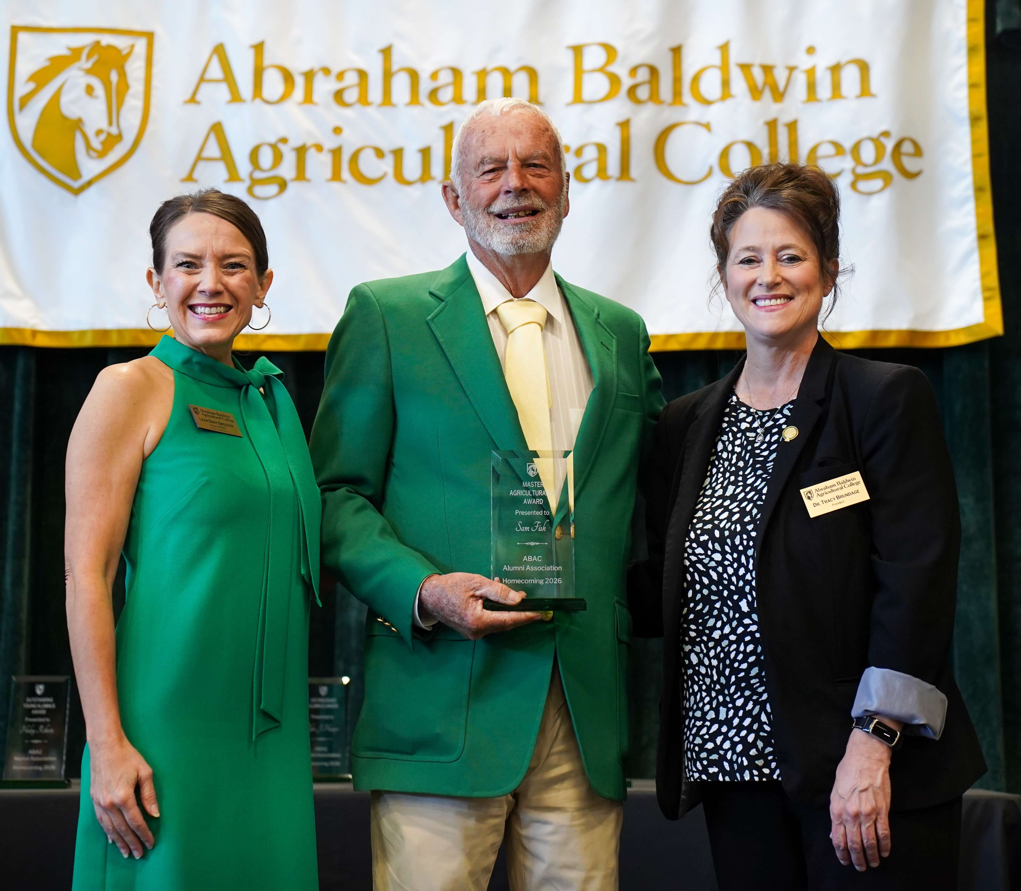 Three people on stage posing for a picture after an award was presented.