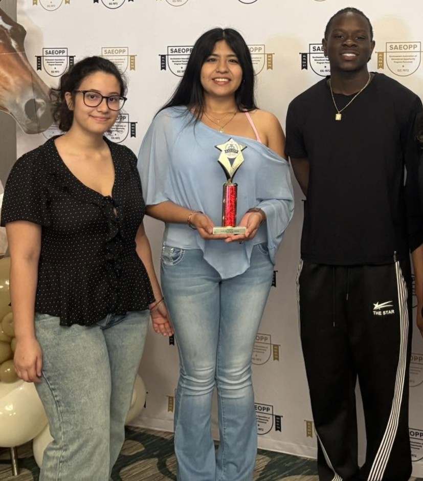 Three students posing with an award